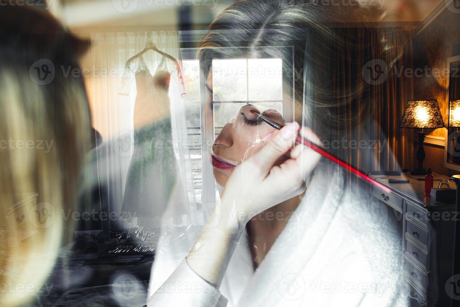 Applying make up to bride photo