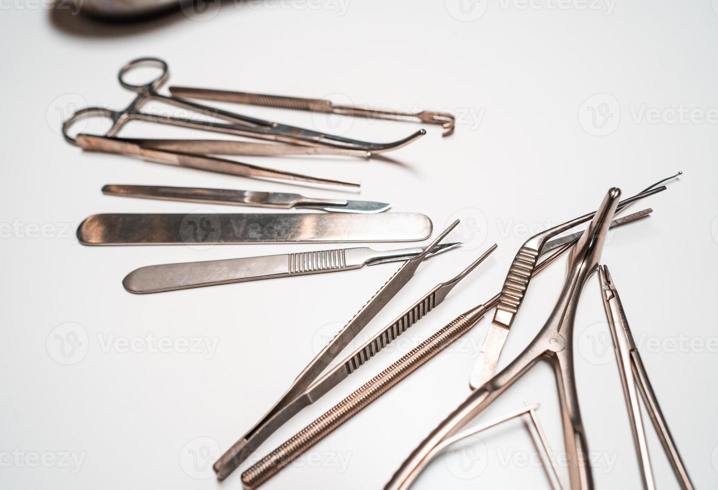 Several surgical instruments lie on a white table photo