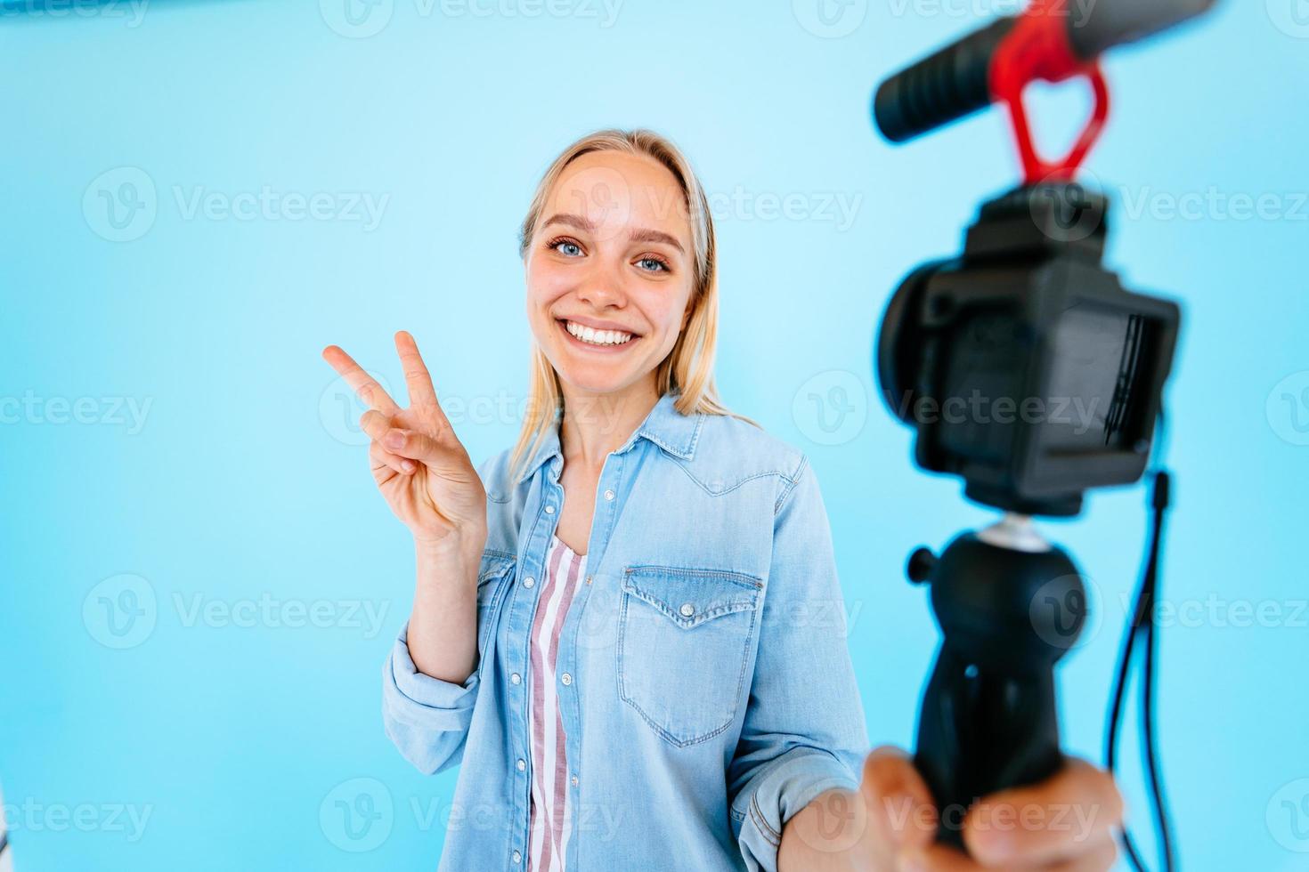 hermosa chica blogger hace sus necesidades en la cámara aislado fondo azul foto