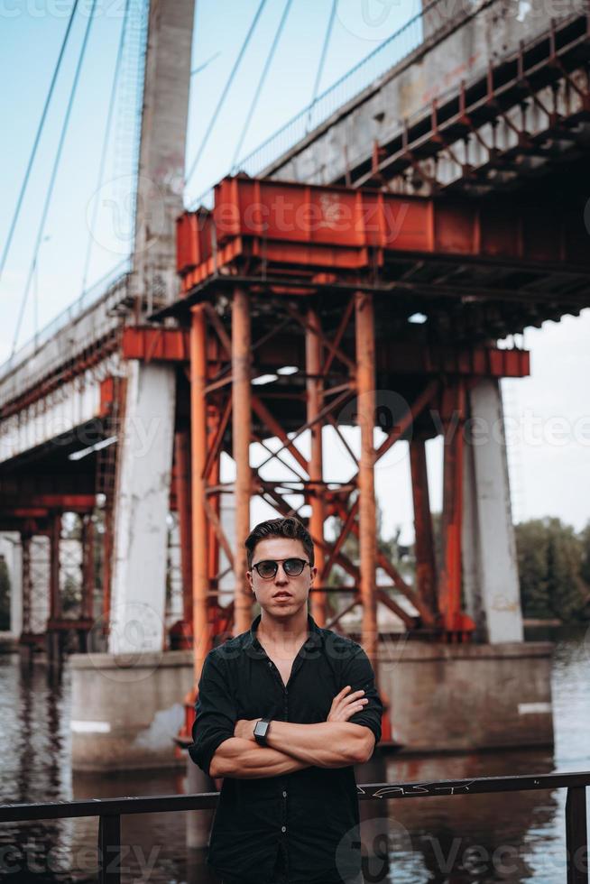 Guy in sunglasses on the background of the bridge photo