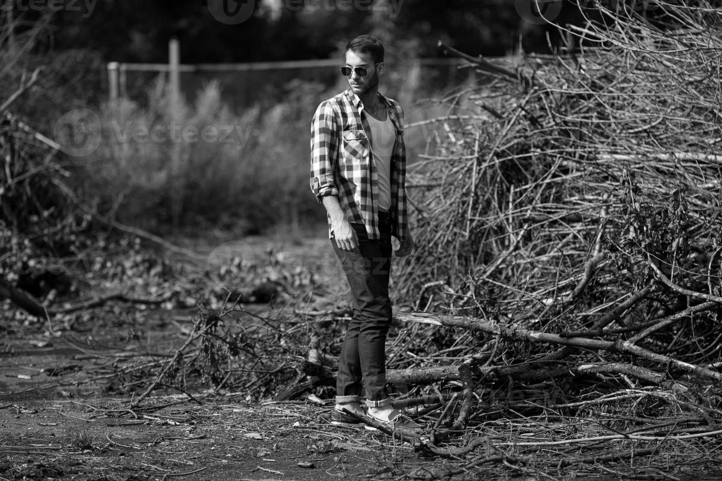 The man in the authentic boots and selvedge jeans  on a the background of branches photo