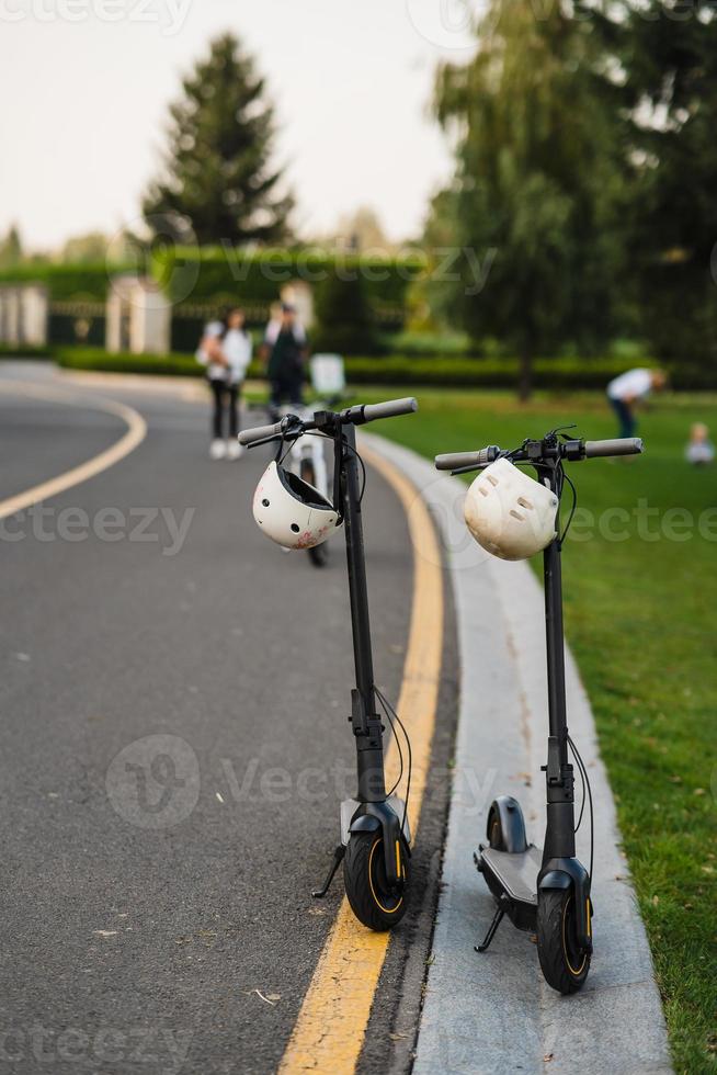 two electric kick scooters or e-scooter parked on the sidelines road photo