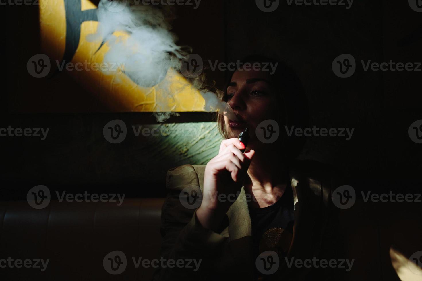 chica se sienta y fuma cigarrillo electrónico foto