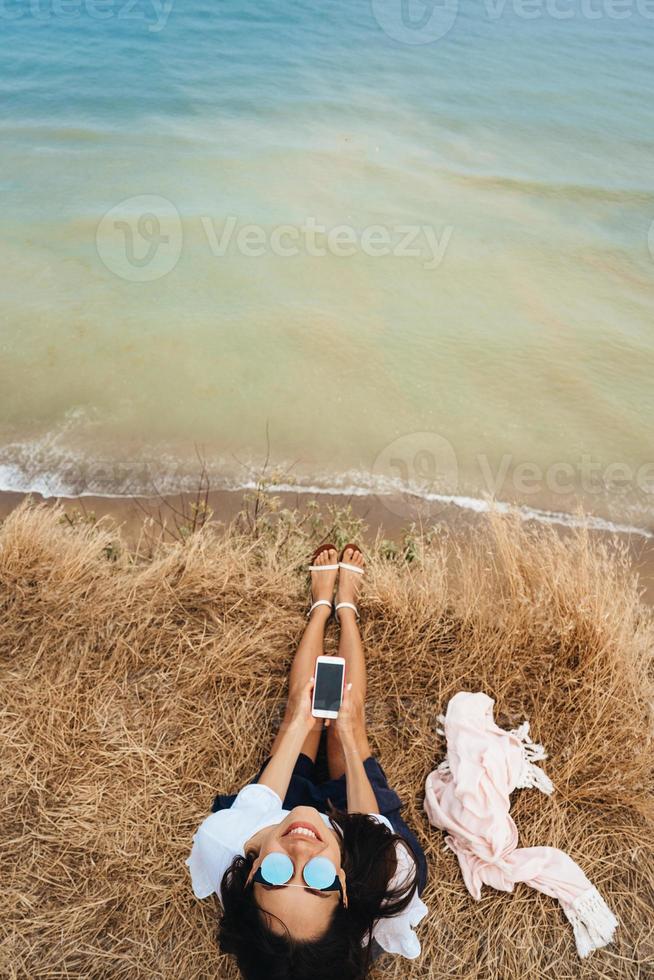 beautiful young girl sitting and holding a smartphone in her hands, top view photo