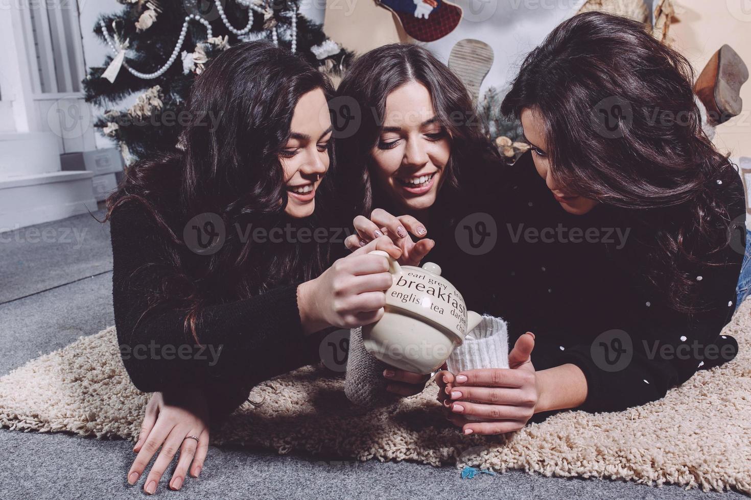 Beautiful girl eating Christmas cookies and drink tea while lying on a carpet. Decorative vintage apartment. photo