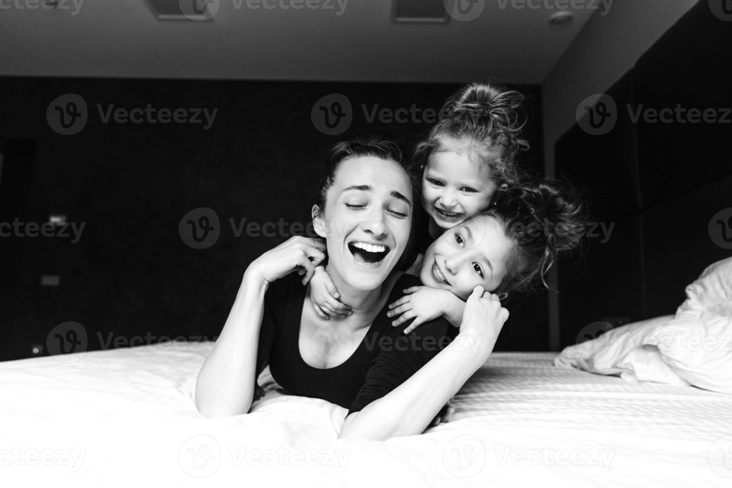 Mom and two daughters have fun on the bed photo