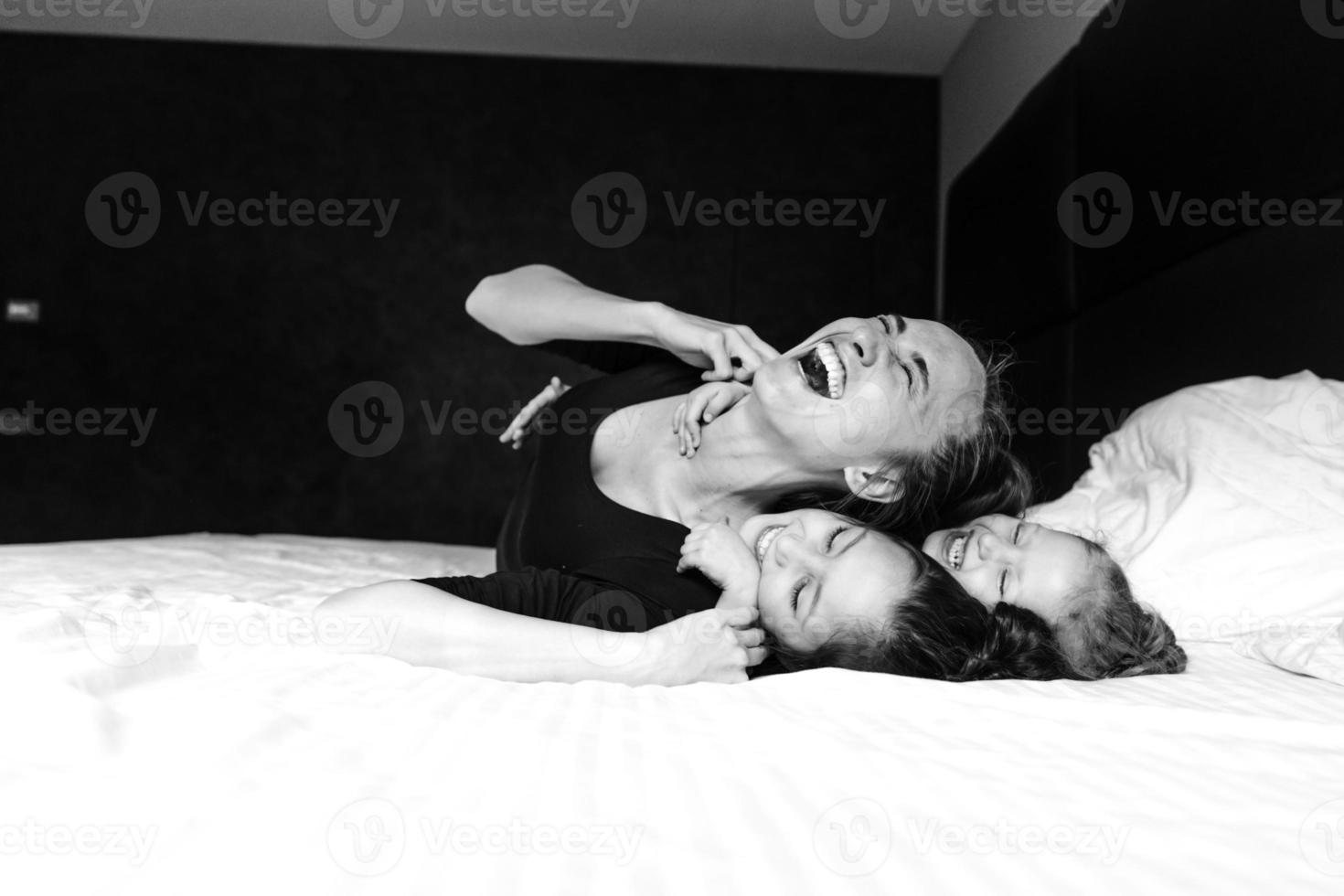 Mom and two daughters have fun on the bed photo