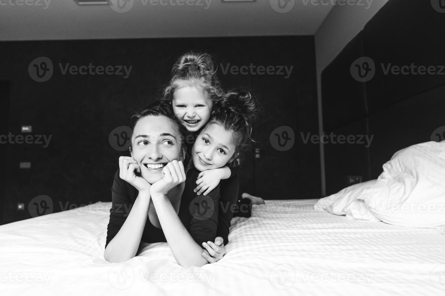 Mom and two daughters have fun on the bed photo