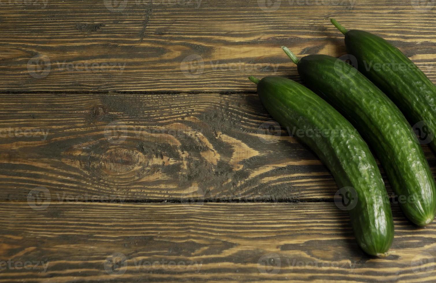 Fresh green cucumbers isolated on wooden background photo