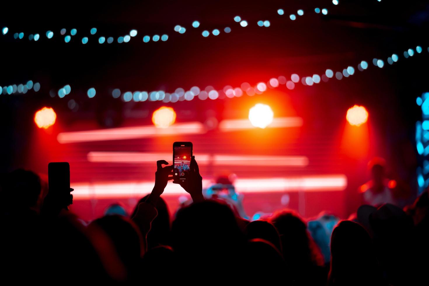 Person close up of recording video with smartphone during a concert. photo