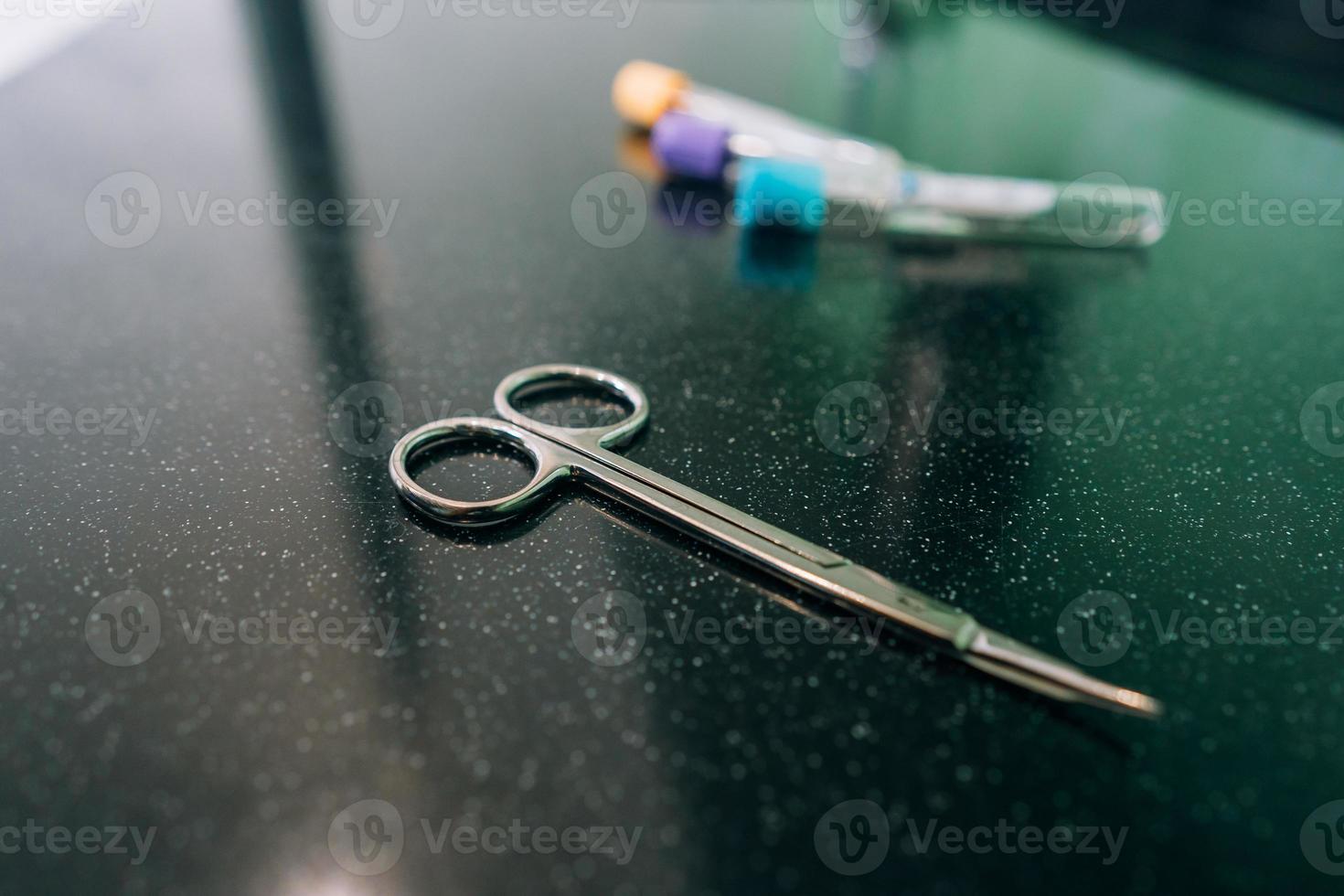 surgical scissors and a few test tubes lie on the table photo
