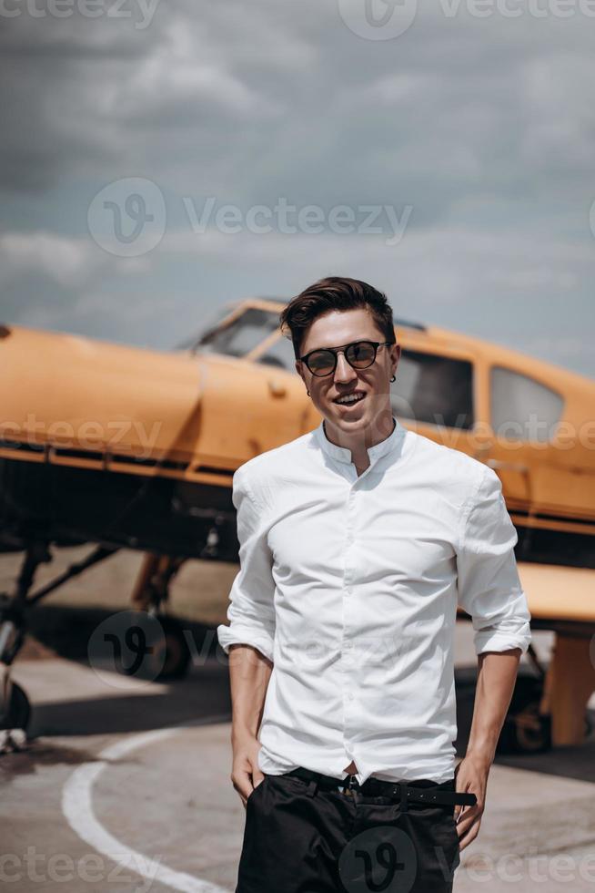 A man standing on the background of a small single engine plane. photo