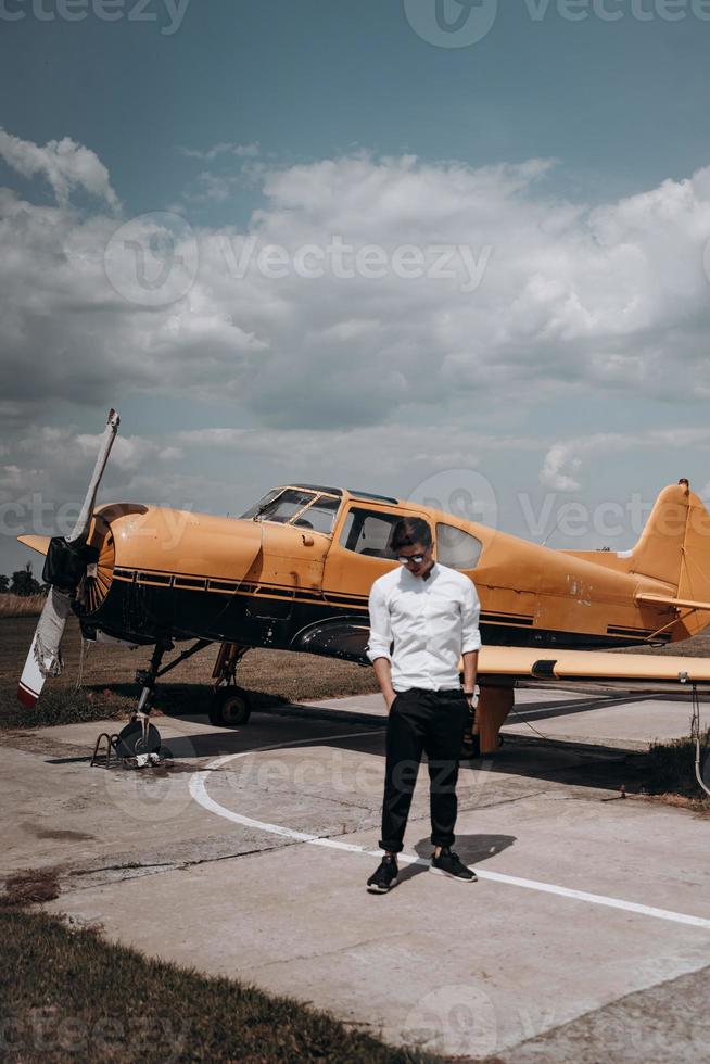 A man standing on the background of a small single engine plane. photo