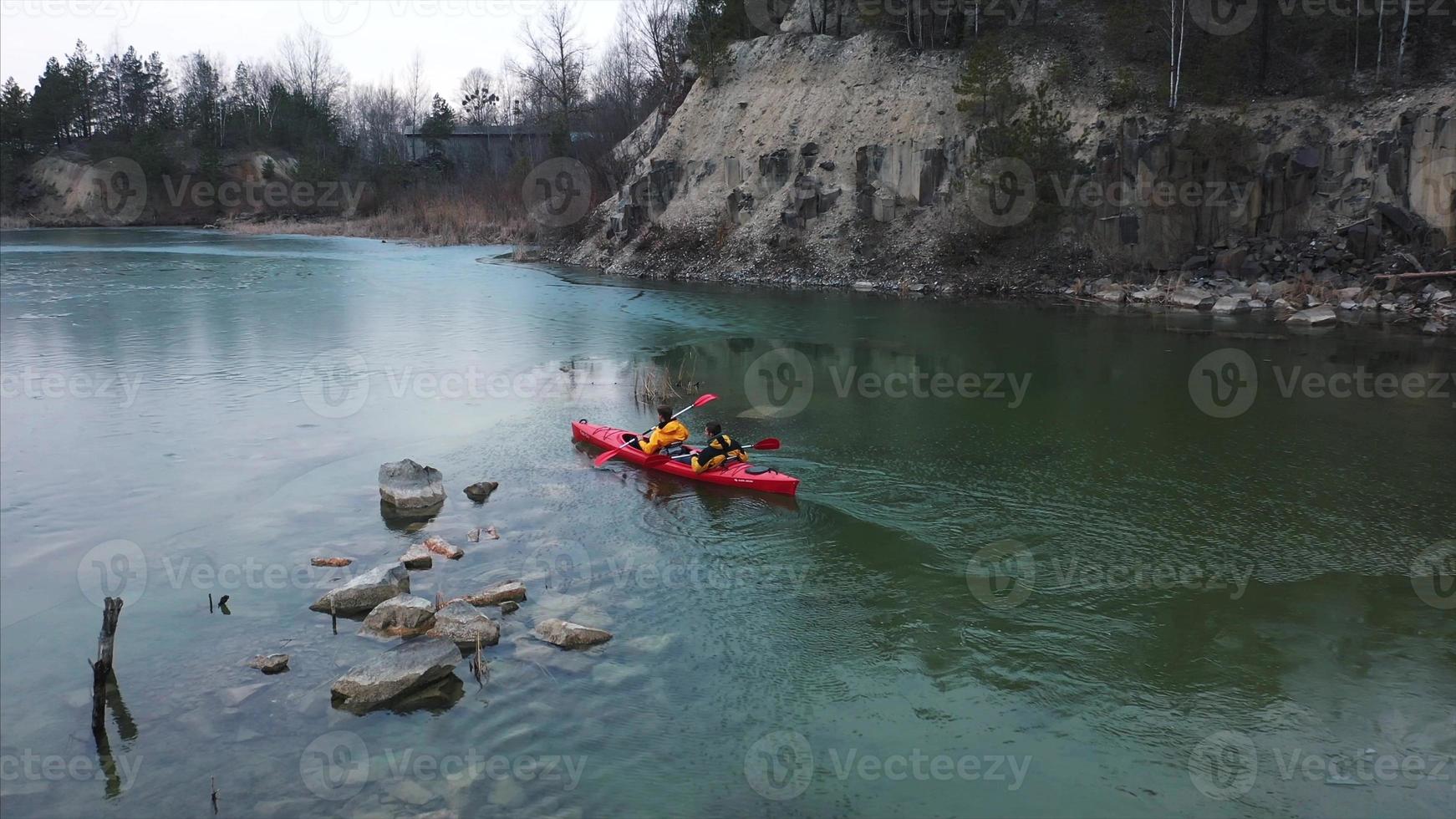 two athletic man floats on a red boat in river photo