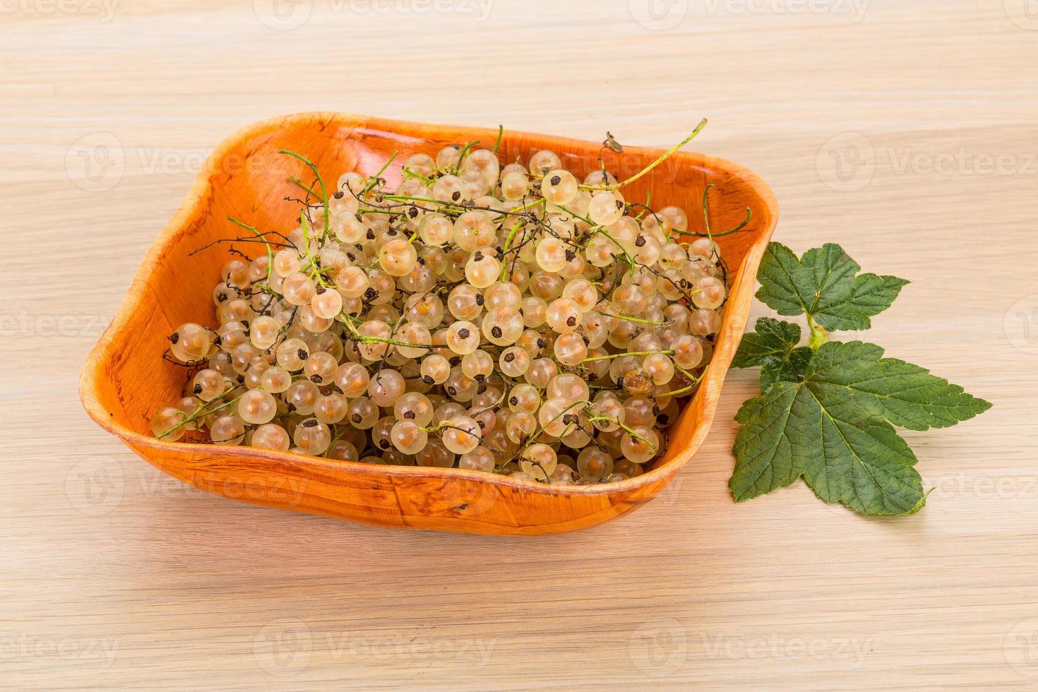 White currant in a bowl on wooden background photo