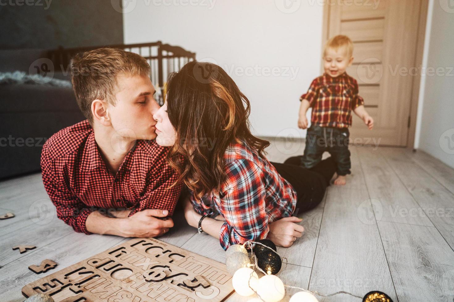 Mom kisses dad on the floor in the nursery photo