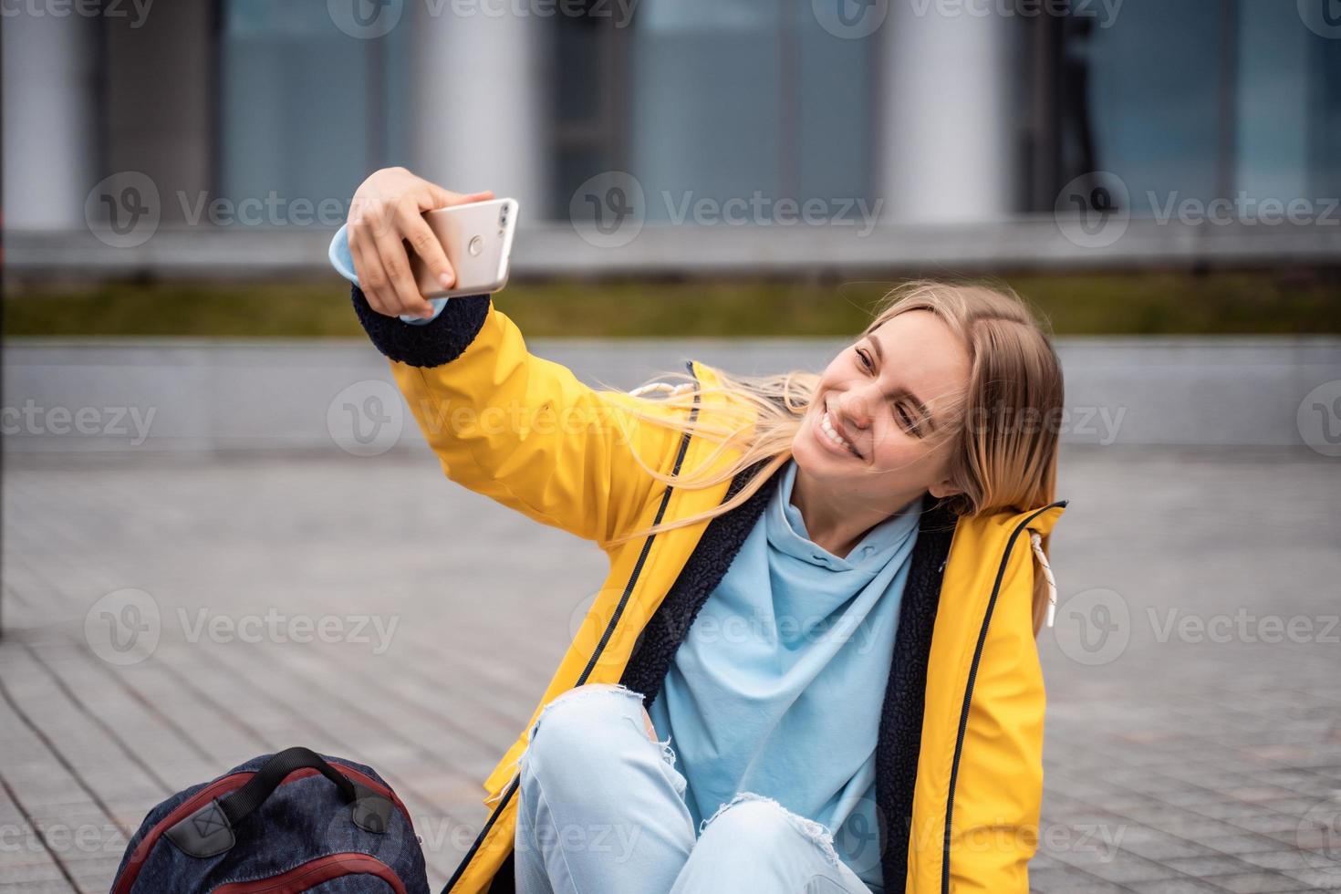 Beautiful girl takes selfie on smartphone and sits on skateboard. photo