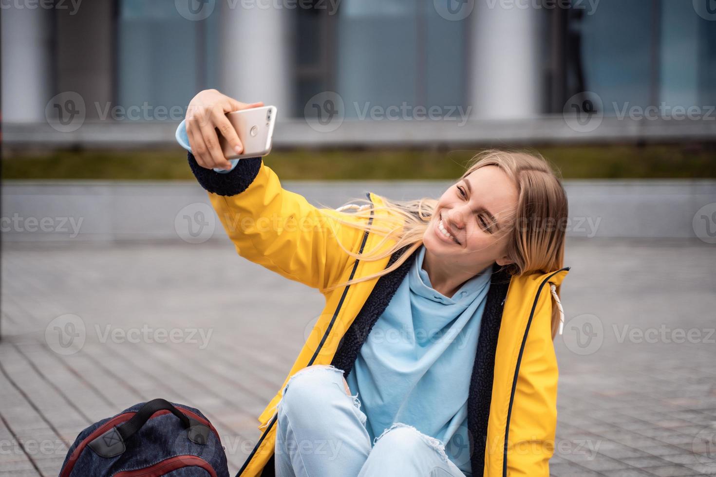 Beautiful girl takes selfie on smartphone and sits on skateboard. photo