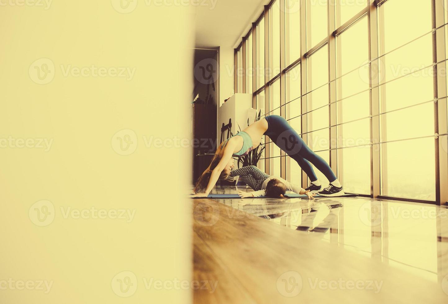 Mother and daughter stretching back in the gym photo