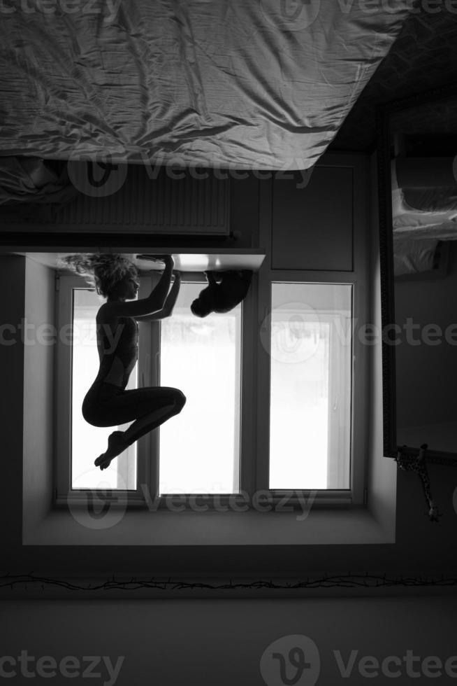 woman doing yoga asana on window sill photo