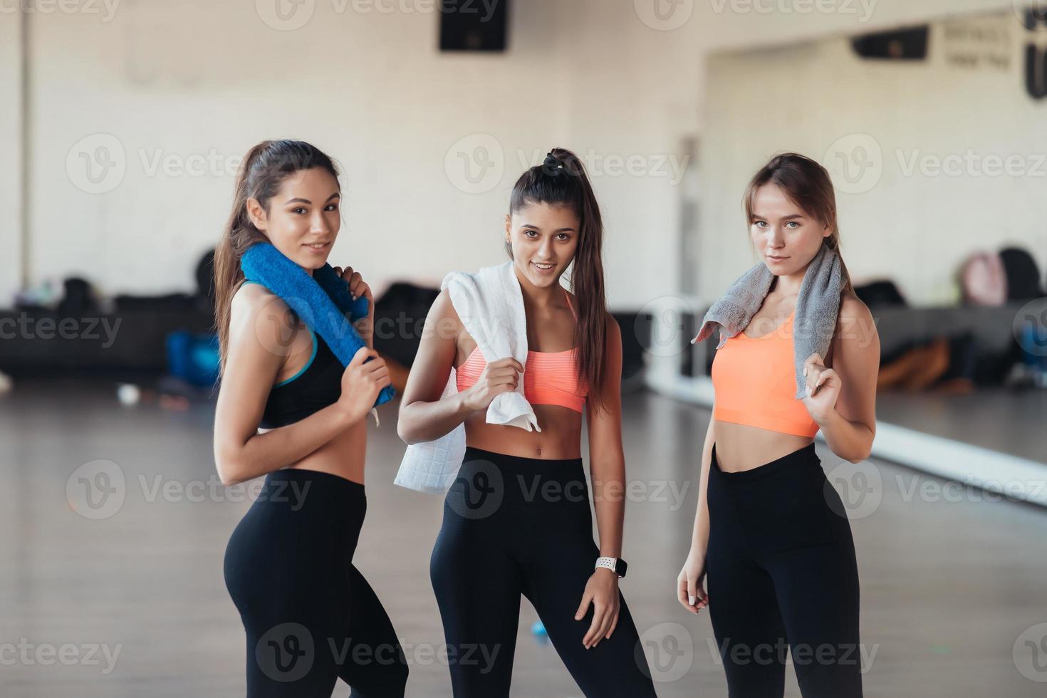 Three happy smiling positive girls after training in the gym. photo