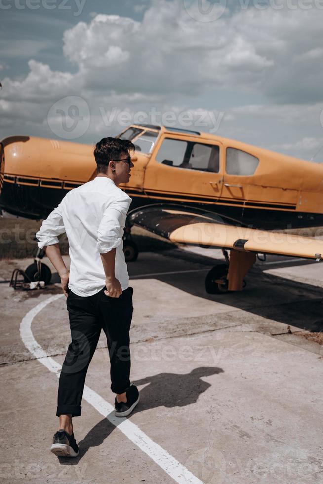 A man standing on the background of a small single engine plane. photo