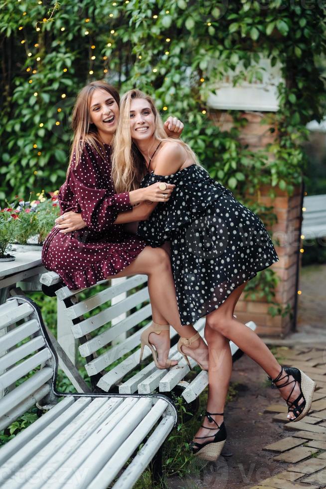 two girls in the park hugging on the bench photo