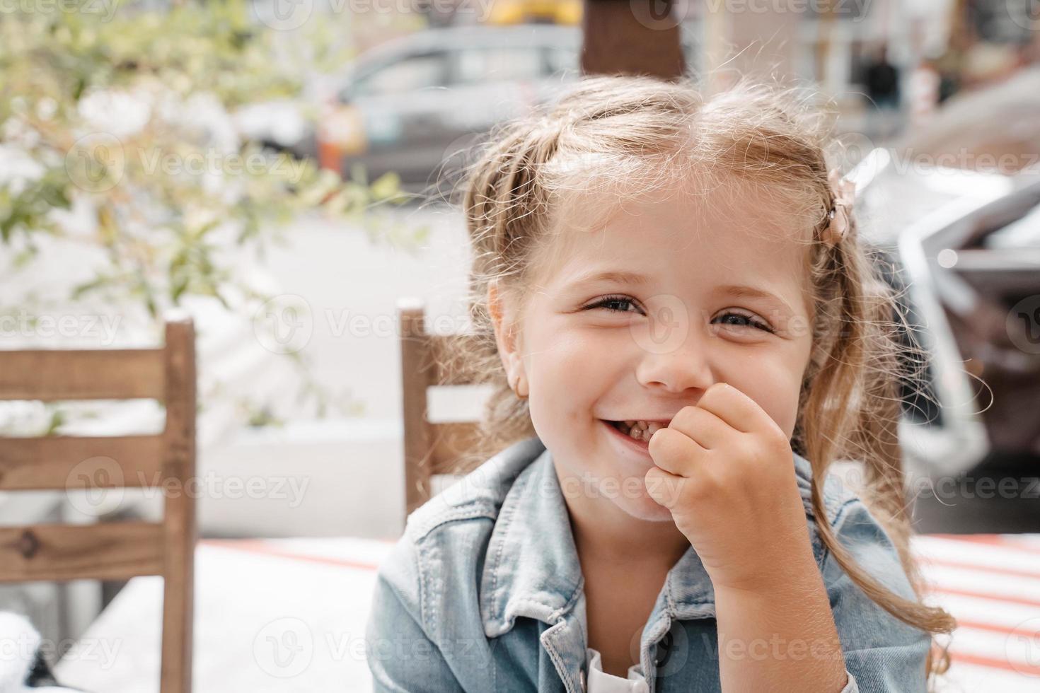 Little girl in a street cafe with french fries photo