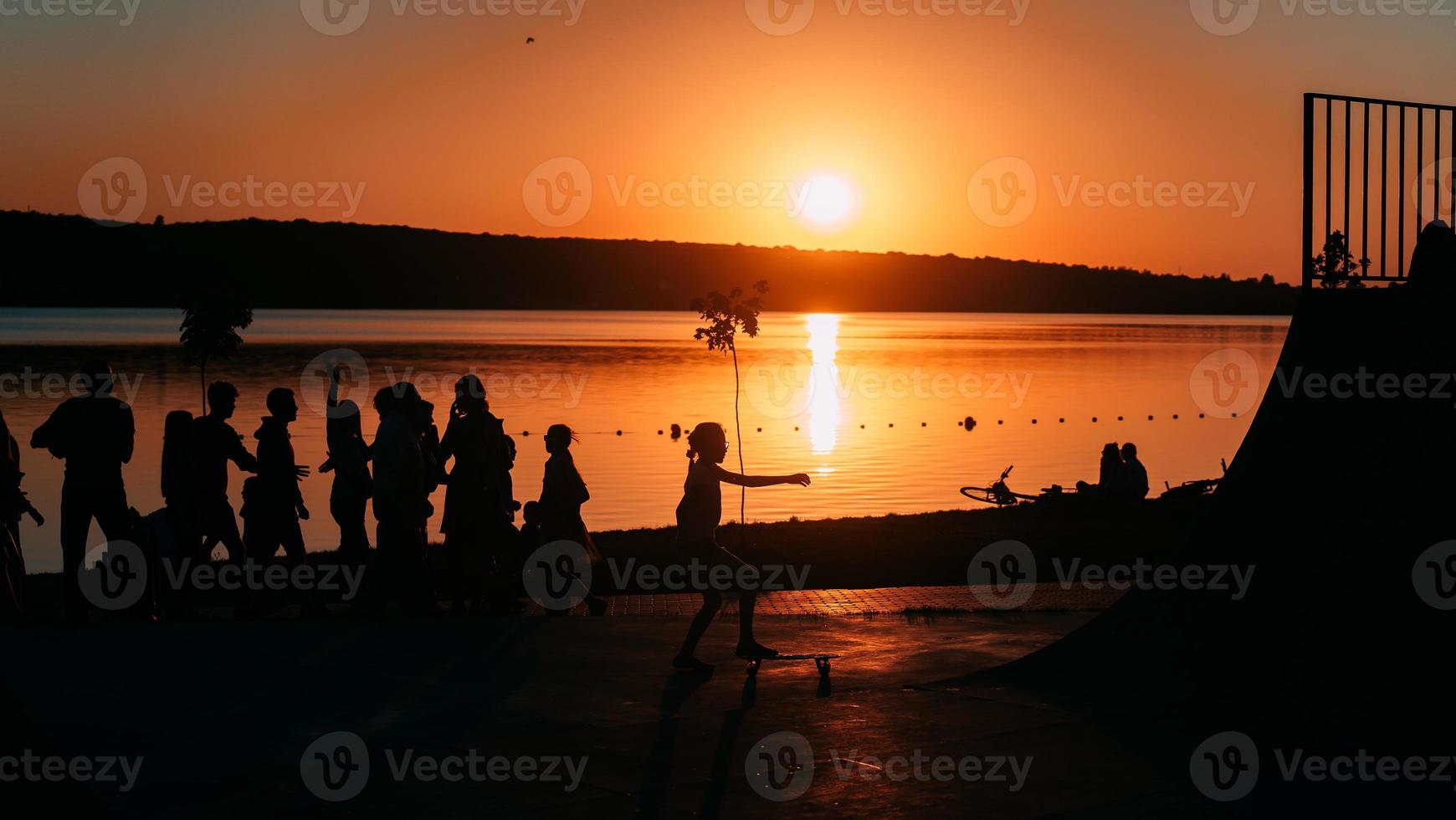 people are resting on a sports field by the river bank photo