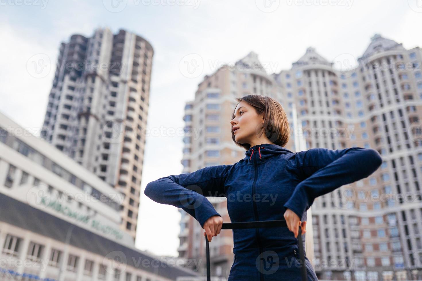 Young sporty woman doing exercises with rubber band outdoor photo