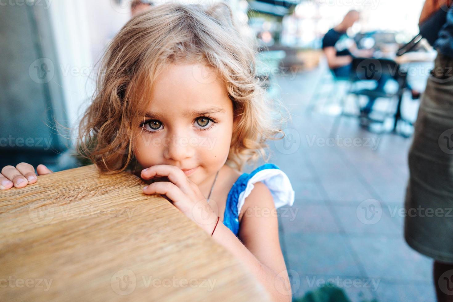 Little girl in a blue dress near a small table photo