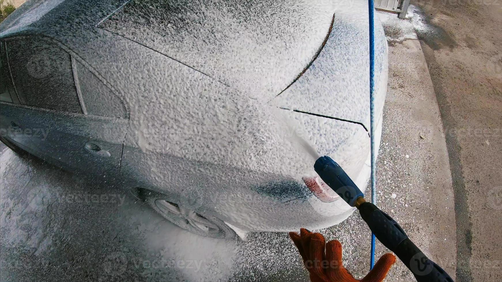 Young man covered soap suds on his car photo