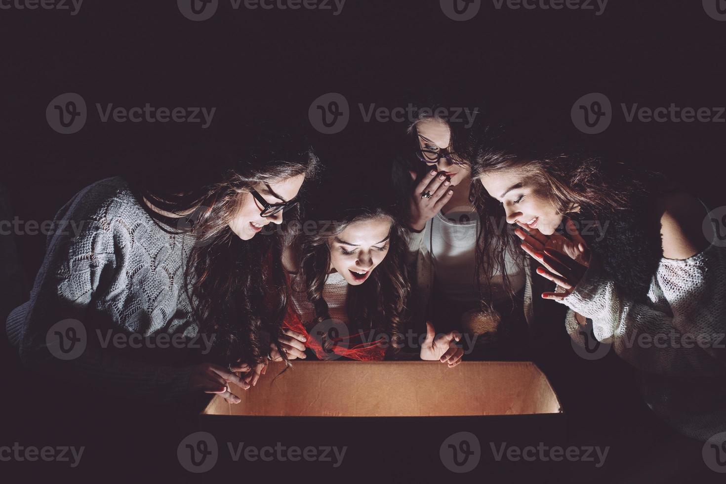 Sisters opens a box with a Christmas present and fascinated looks inside photo