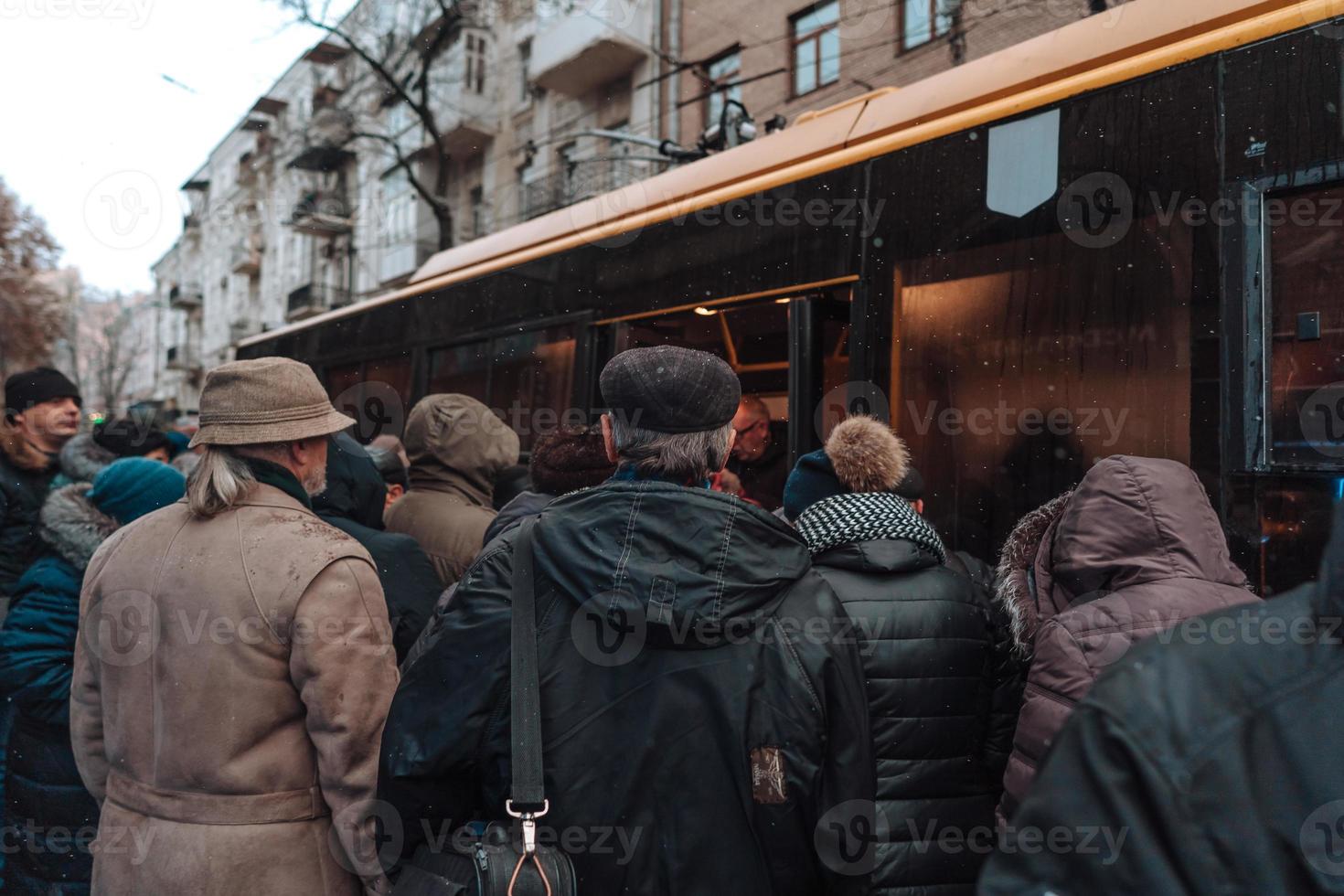 Many unidentified people are waiting for city transport at the bus stop photo