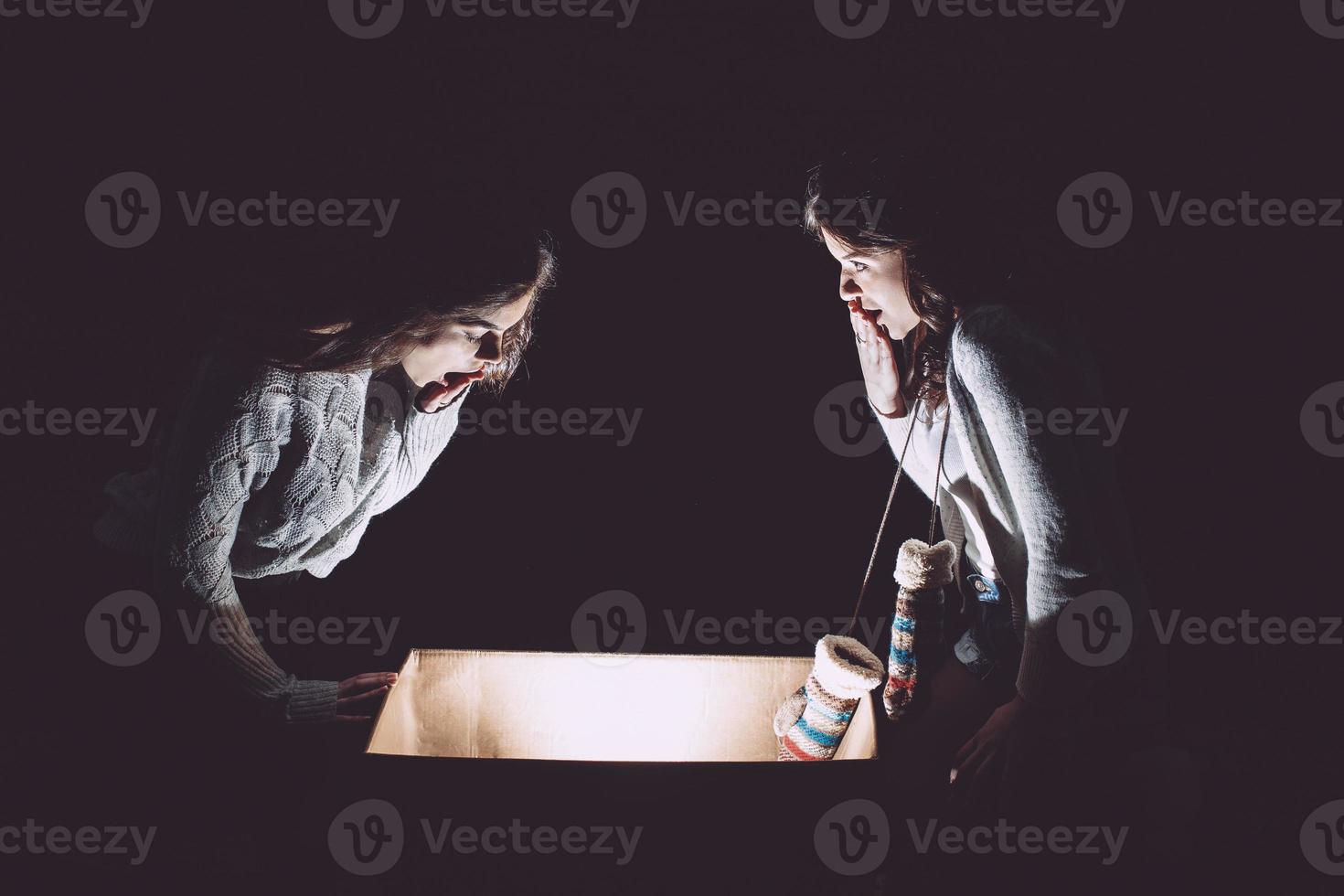 las hermanas abren una caja con un regalo de navidad y miran fascinadas dentro foto