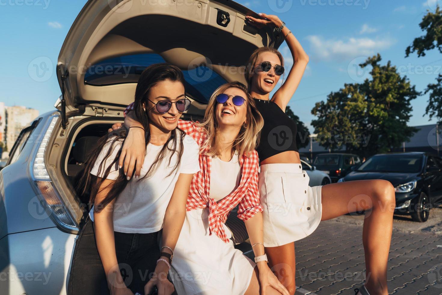 Three young woman posing for the camera the car park. photo