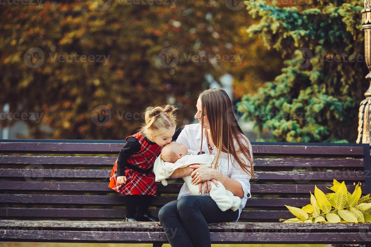 mother and two daughters rest on a bench photo
