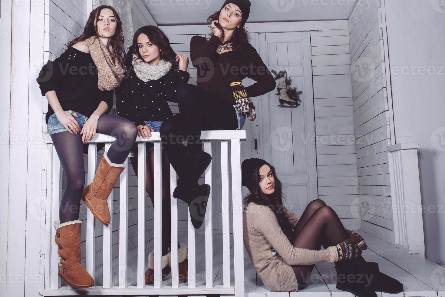 Four stylish models posing sitting on the fence. Christmas background photo