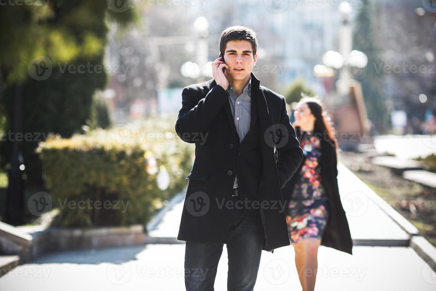 businessman talking on the phone while woman comes to him photo