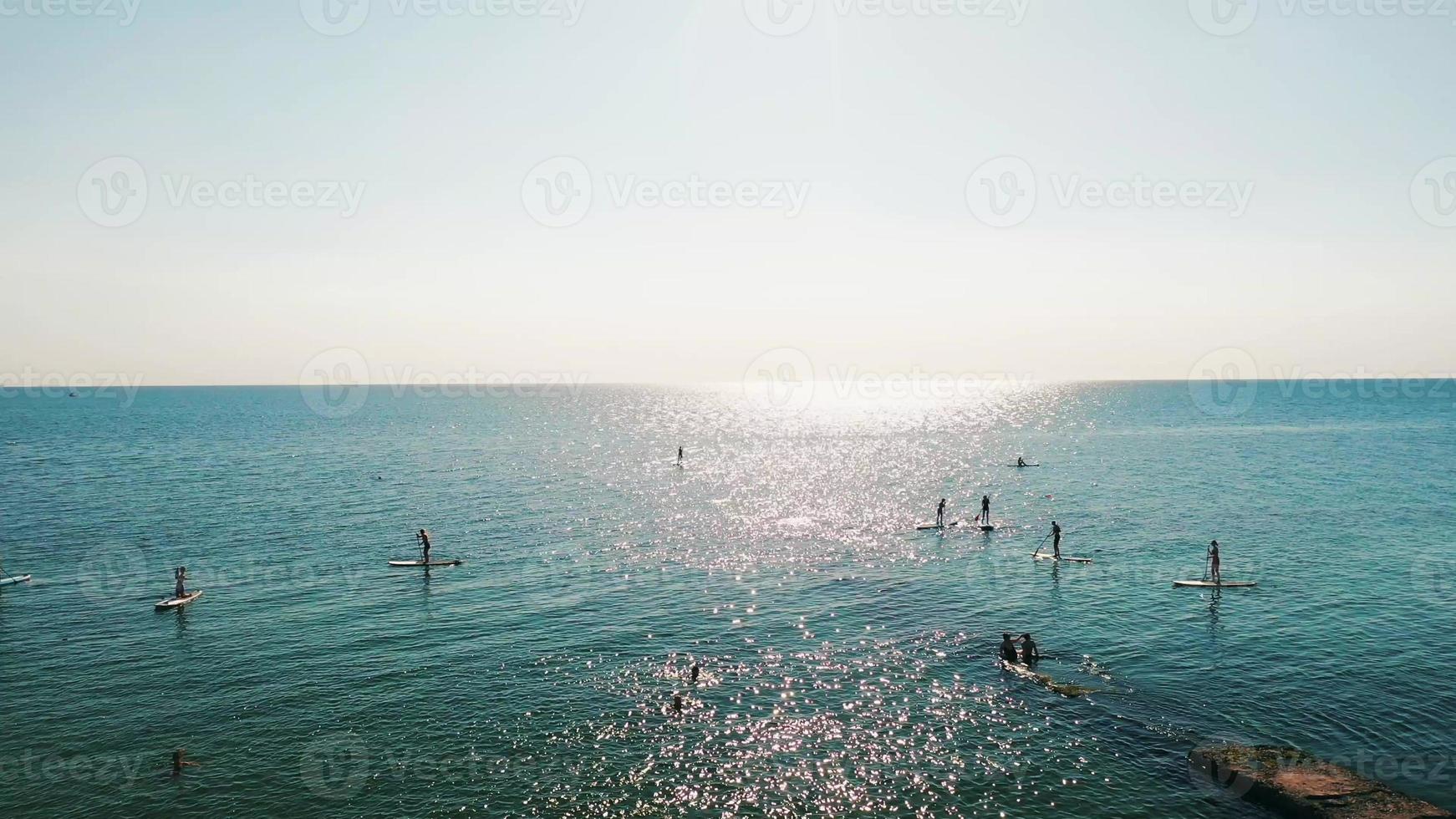 Tourists floating on SUP Board in blue sea. Clip. photo