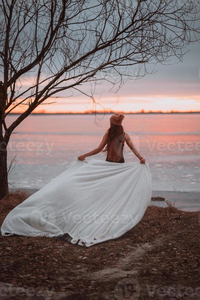 Beautiful young girl in a swimsuit on the shore of a frozen lake photo