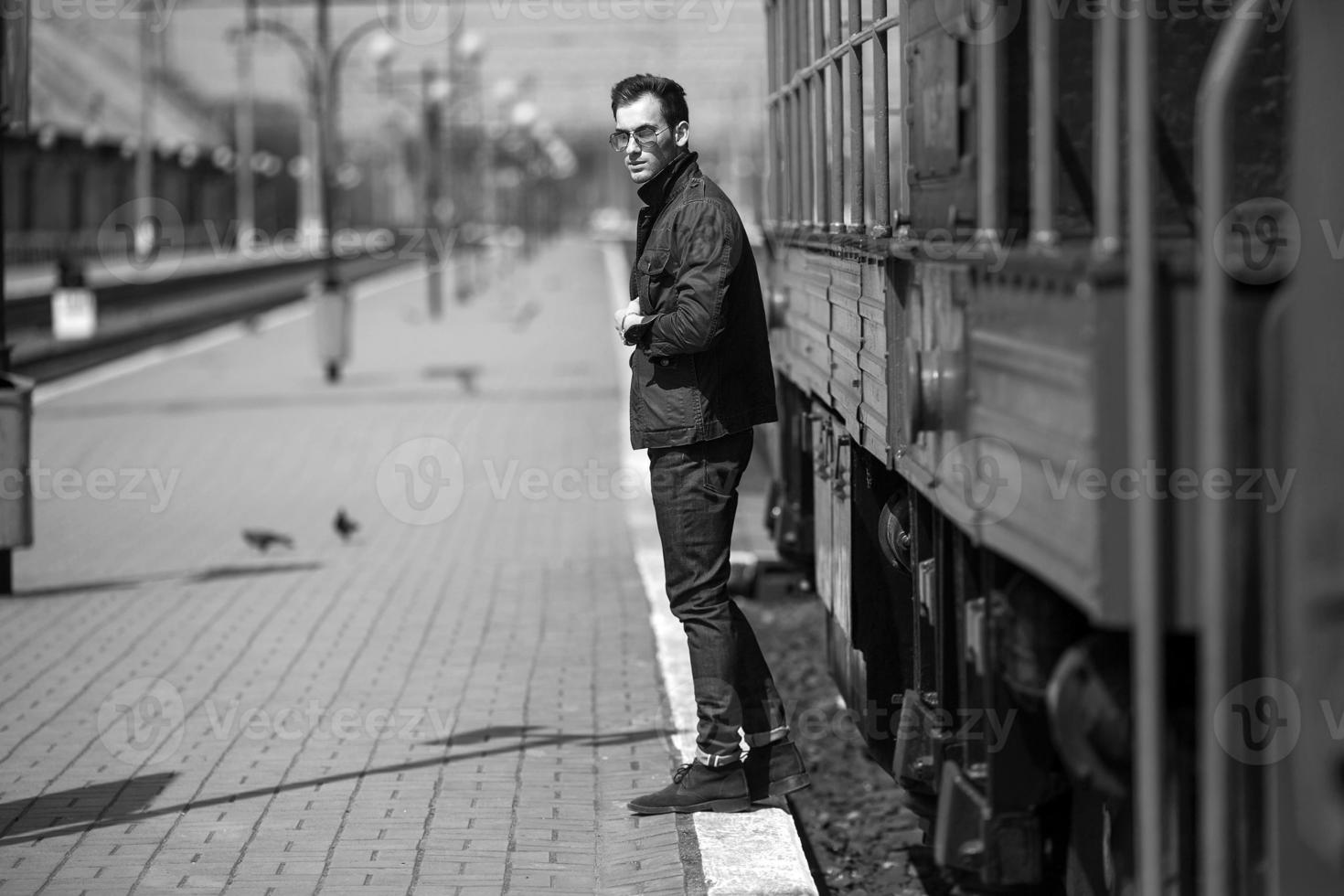 un hombre vestido con jeans en el fondo del tren y la estación foto