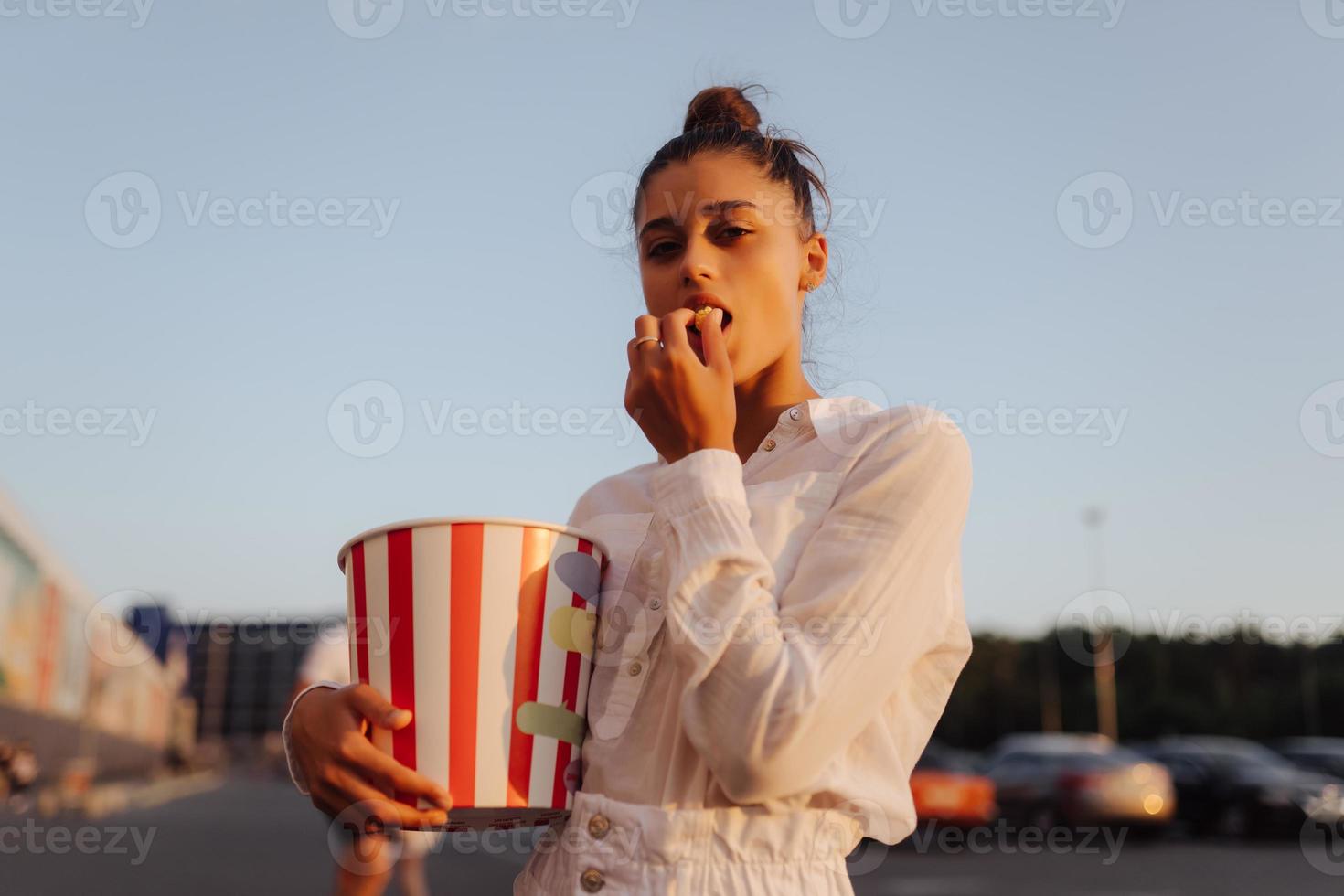 Young cute woman holding popcorn in a shopping mall parking lot photo