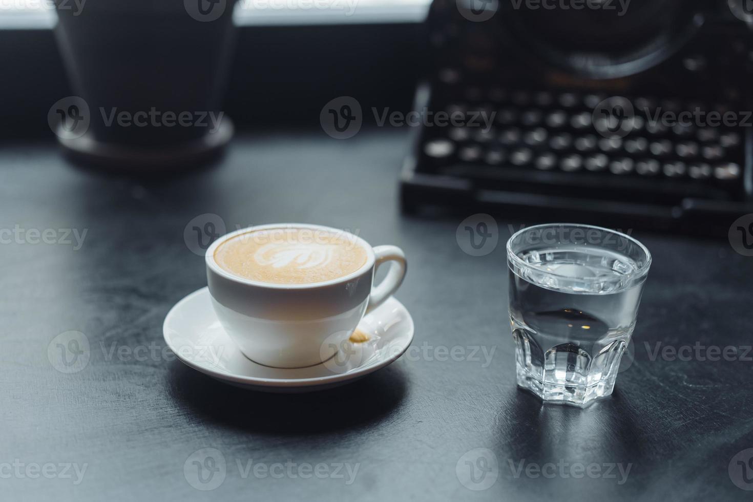 A cup of cafe latte coffee in a ceramic cup and a glass of water photo