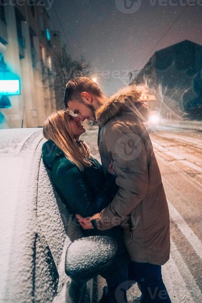 Young adult couple kissing each other on snow covered street photo