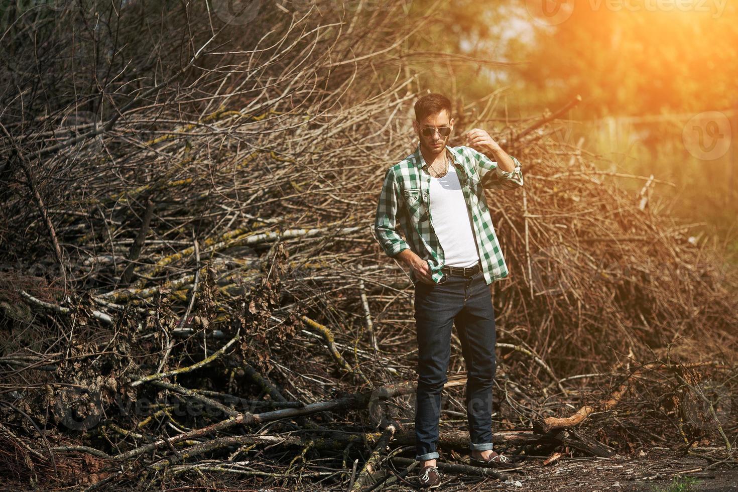 The man in the authentic boots and selvedge jeans  on a the background of branches photo