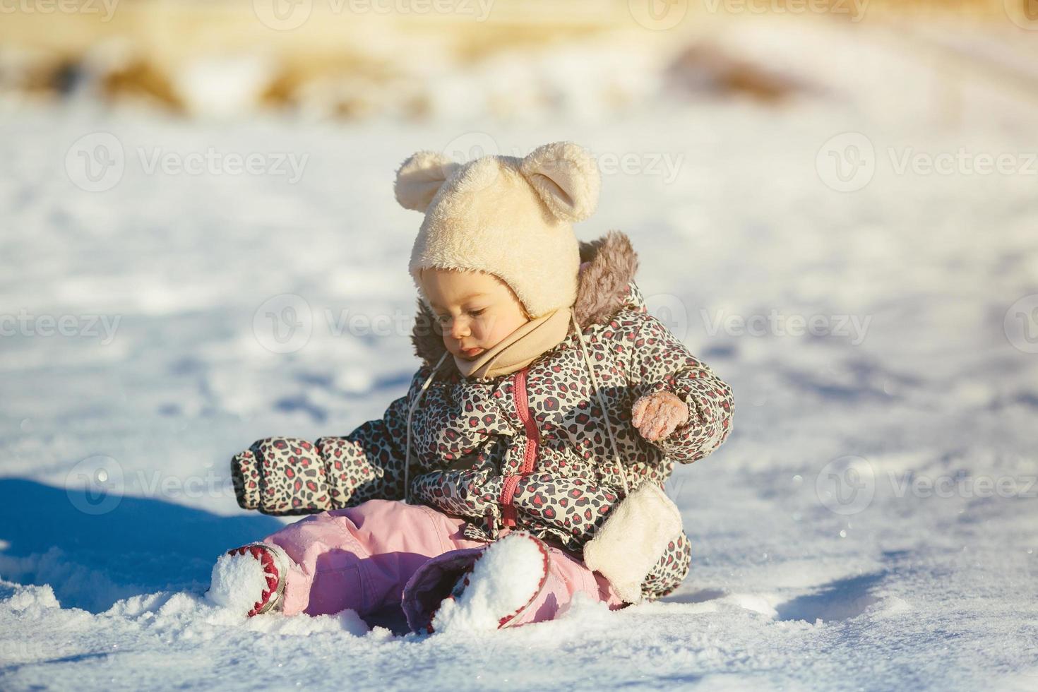 Little girl sitting in the snow photo