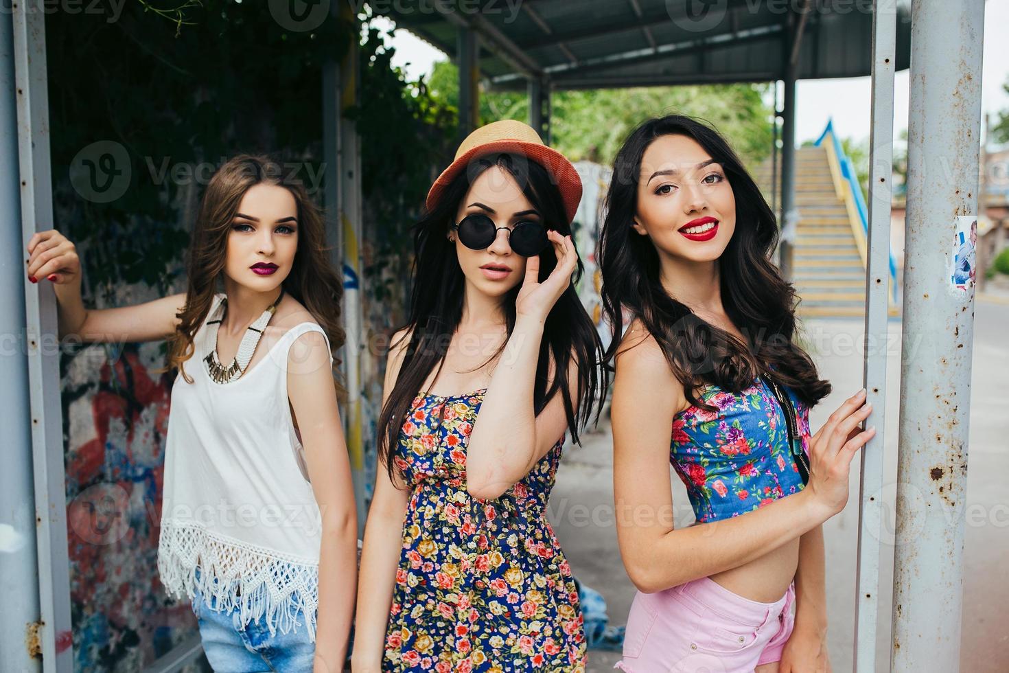 Three beautiful young girls at the bus stop photo