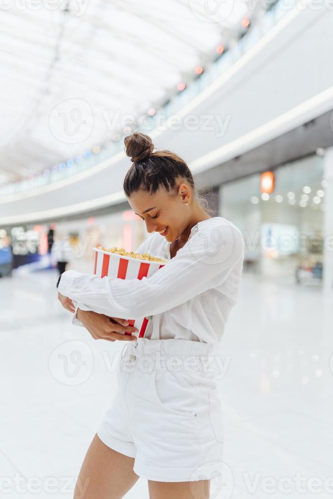 young cute woman holding popcorn in the mall background photo