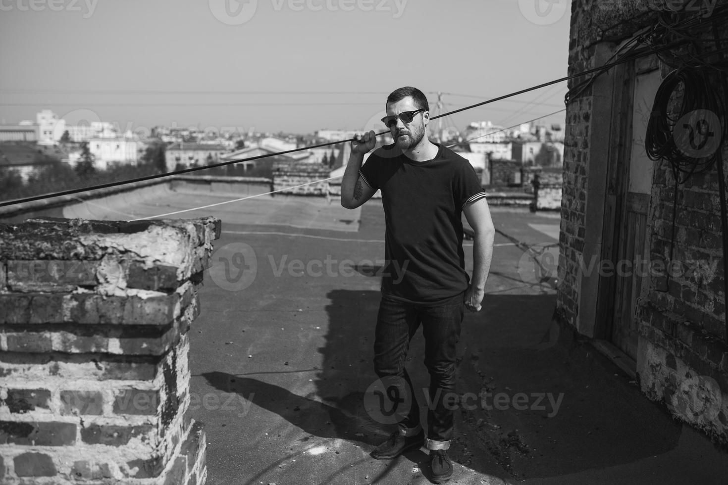 El hombre de las botas auténticas y el orillo de jeans en el techo del edificio en el casco antiguo foto